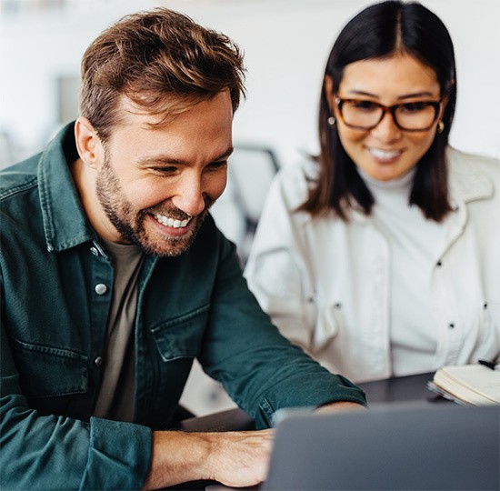 A man and a woman behind a computer screen