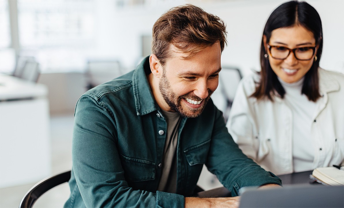 A man and a woman behind a computer screen