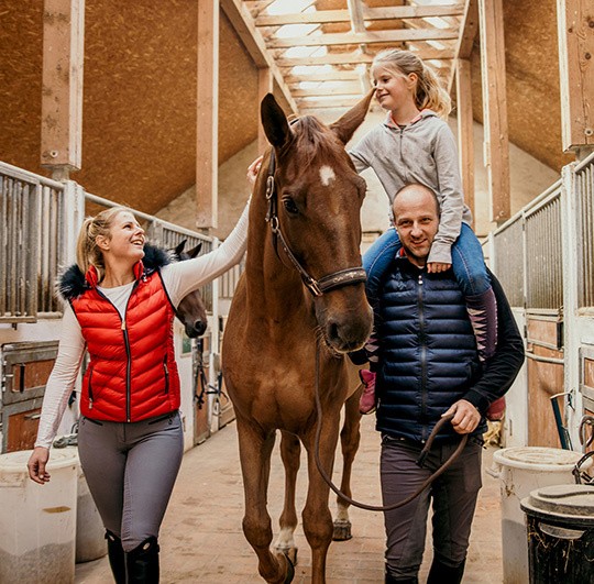 A family in a stable with a horse