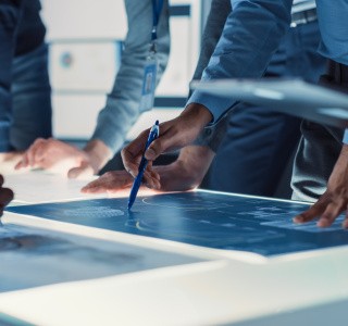 Ingénieurs, scientifiques et développeurs réunis autour d'une table de conférence éclairée dans un centre de recherche technologique